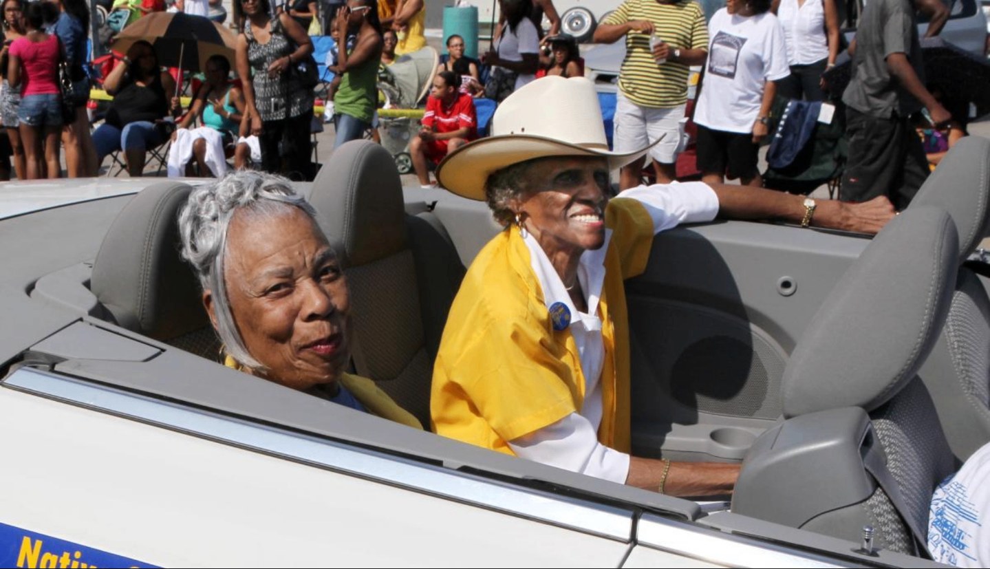 Two elders riding in a convertible during the homecoming parade